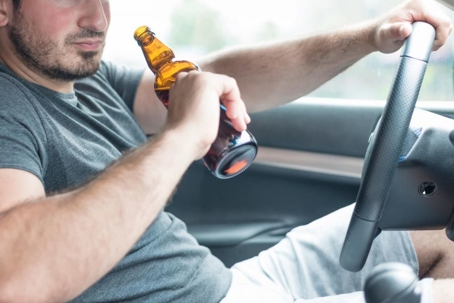 Man drinking beer behind the wheel of a car