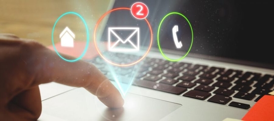 Person using a laptop and an email, phone, and home icon appear