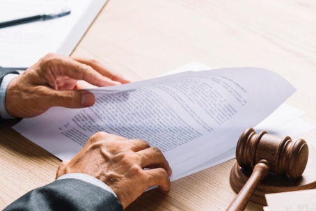 person flipping through documents with a gavel on the table nearby