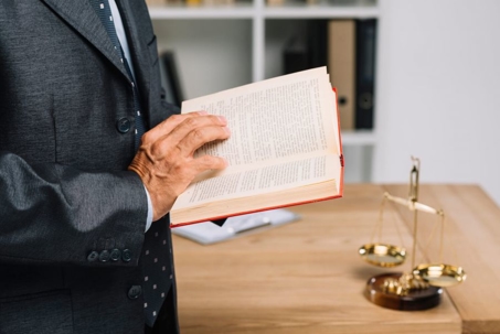 Man reading a book with the Scales of Justice on the table behind him
